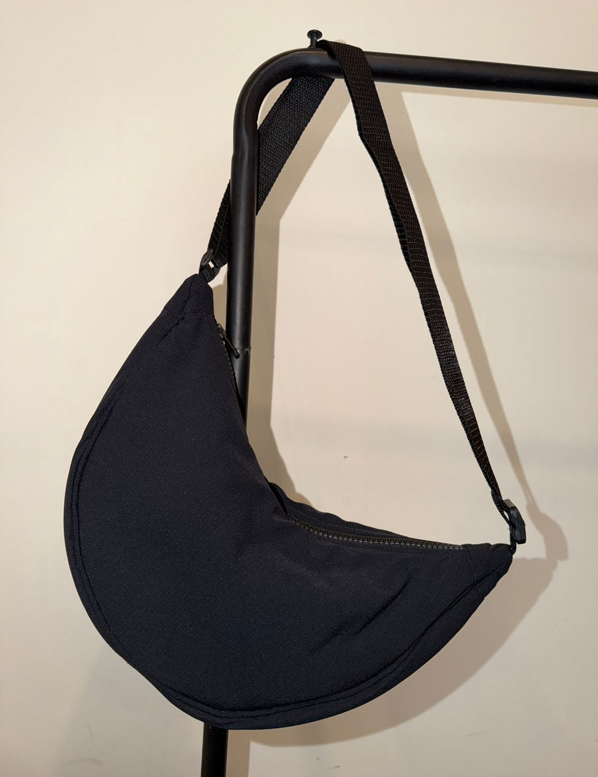 Black crescent crossbody bag hanging on a rack