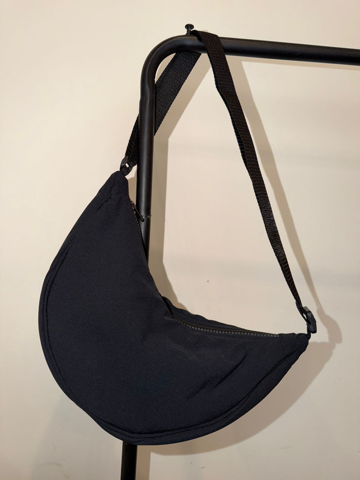 Black crescent crossbody bag hanging on a rack